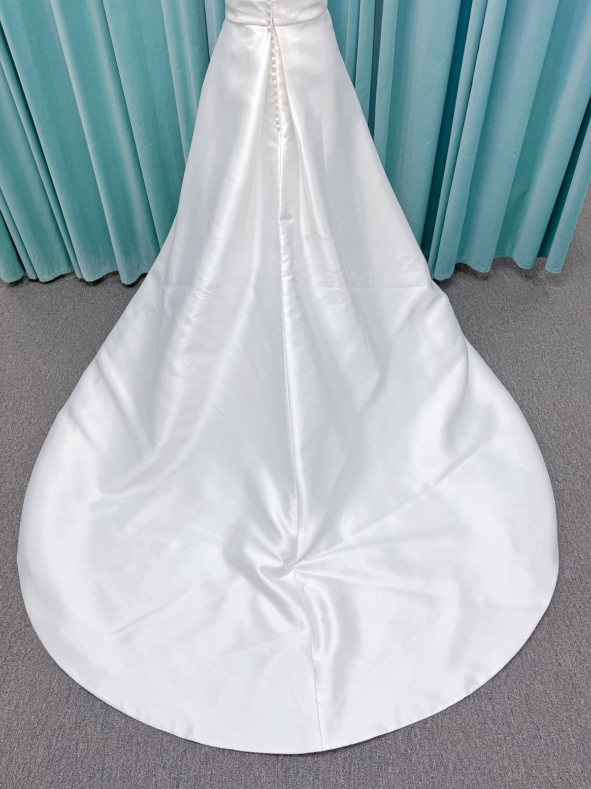 Moonlight Bridal J6978 Livana A-line wedding dress on mannequin with strapless scoop neckline, ruched mikado bodice, asymmetrical draped waist, high front slit, and chapel train