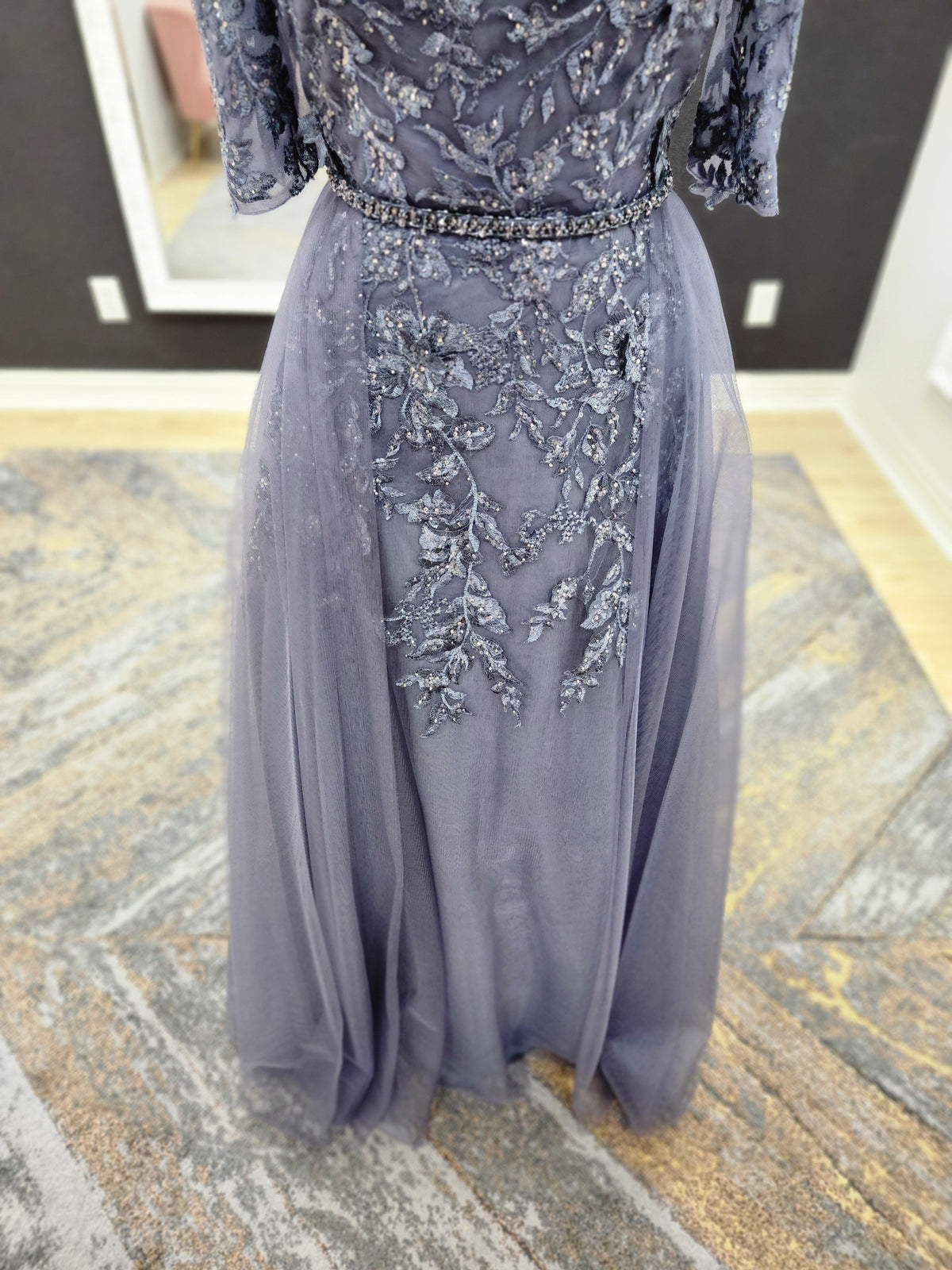 Morilee MGNY 72834 off-the-shoulder mother of the bride gown with embroidered lace bodice, sheer sleeves, and flowing A-line skirt with detachable overskirt.