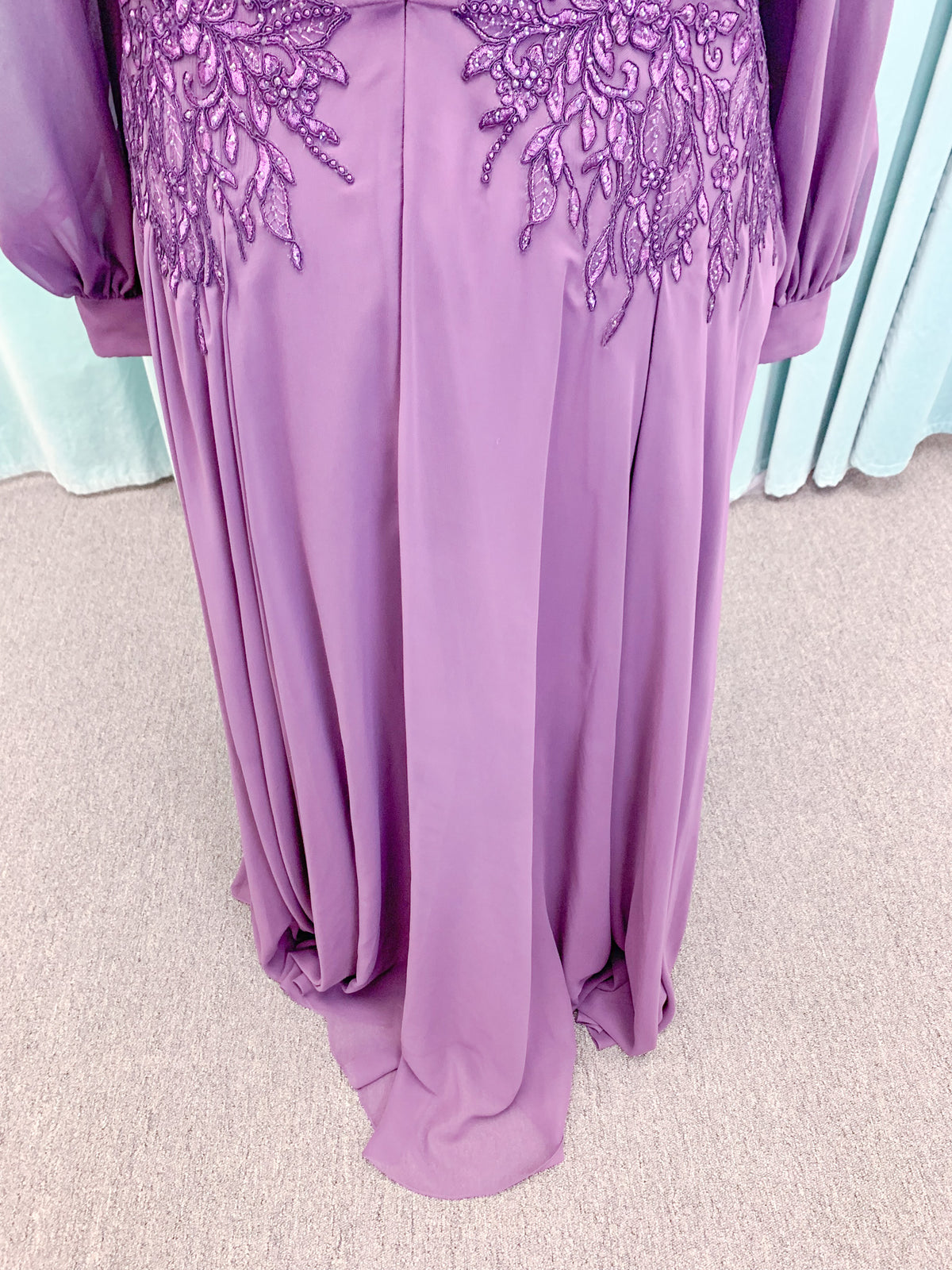 Morilee MLNY 72717 plus size A-line mother of the bride dress on mannequin with draped V-neckline, sheer bishop sleeves, beaded lace appliques at the shoulders and waist, and flowing chiffon skirt with sweep train
