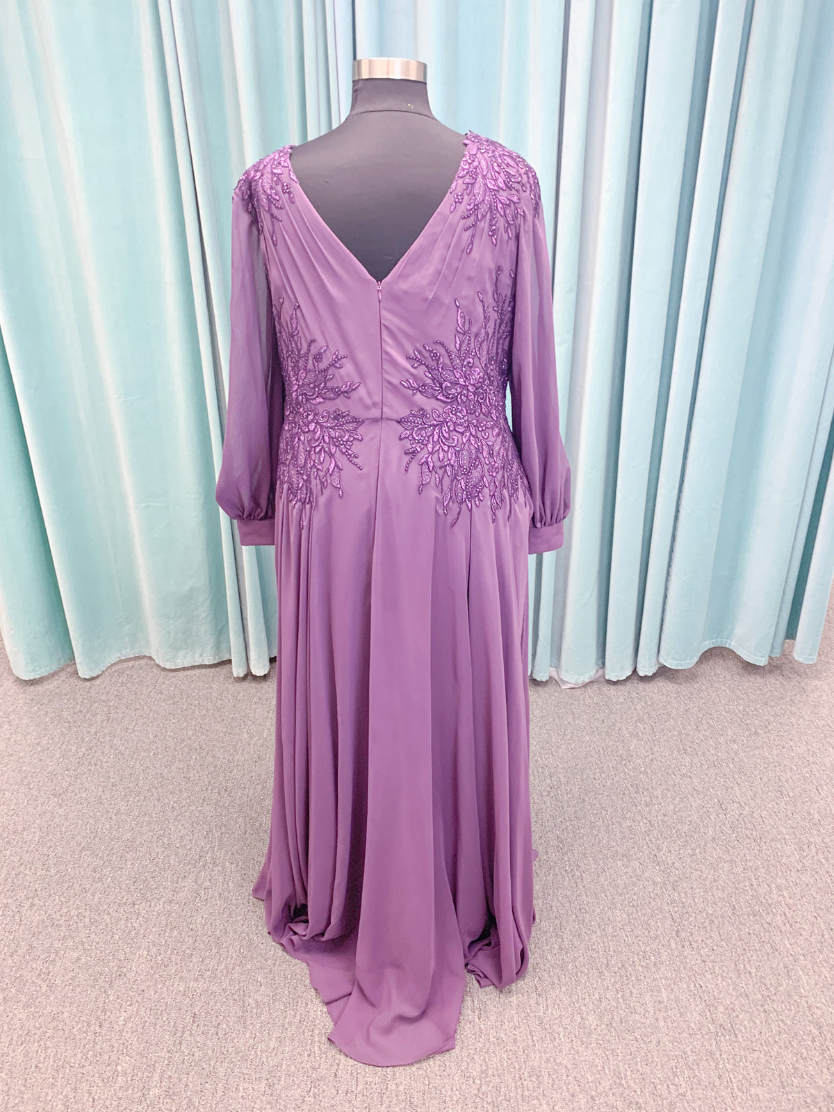 Morilee MLNY 72717 plus size A-line mother of the bride dress on mannequin with draped V-neckline, sheer bishop sleeves, beaded lace appliques at the shoulders and waist, and flowing chiffon skirt with sweep train