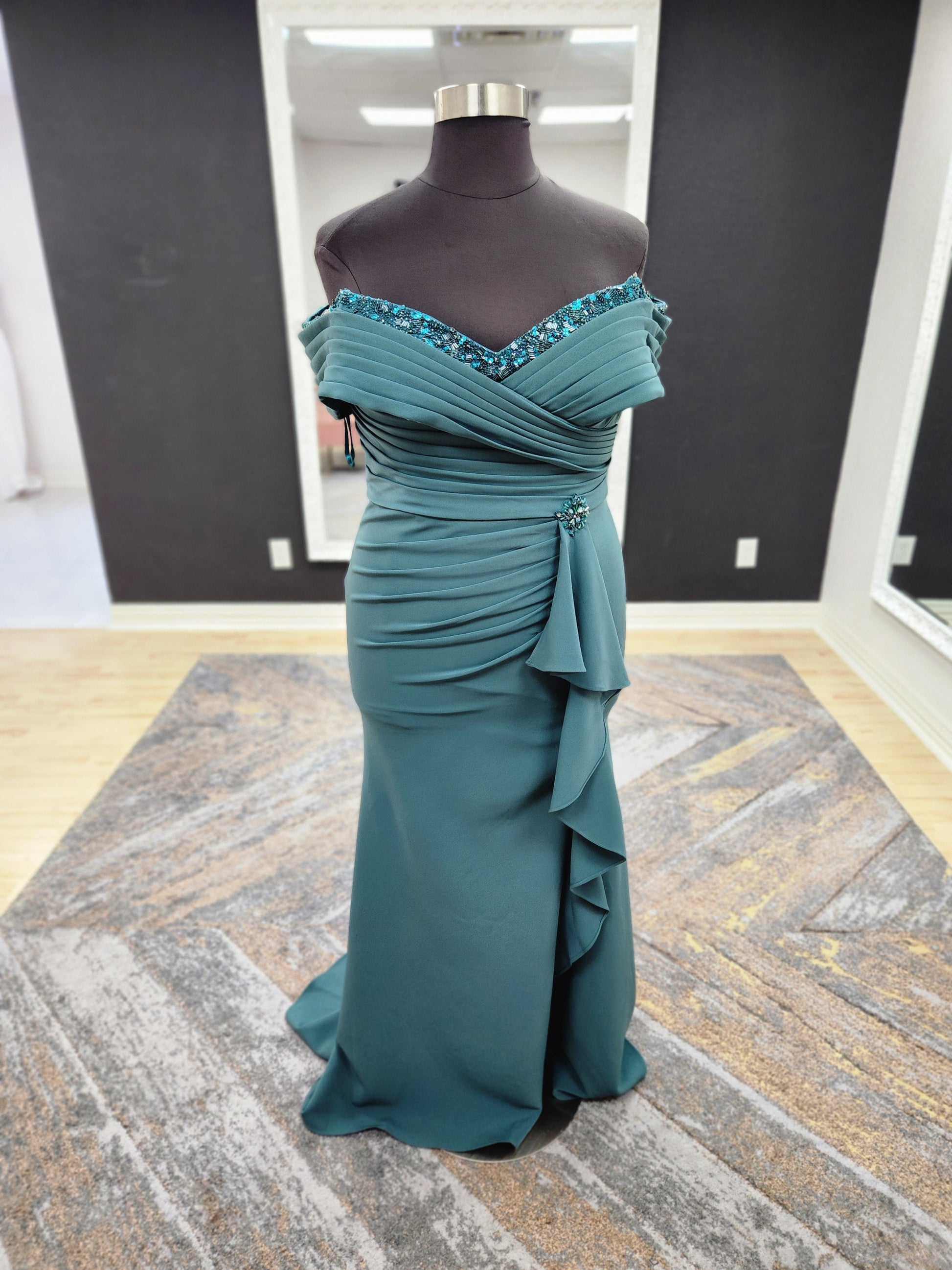 Morilee MGNY 72827 off-the-shoulder scuba crepe mother of the bride gown with draped bodice, cascading ruffle slit, and fitted mermaid silhouette.