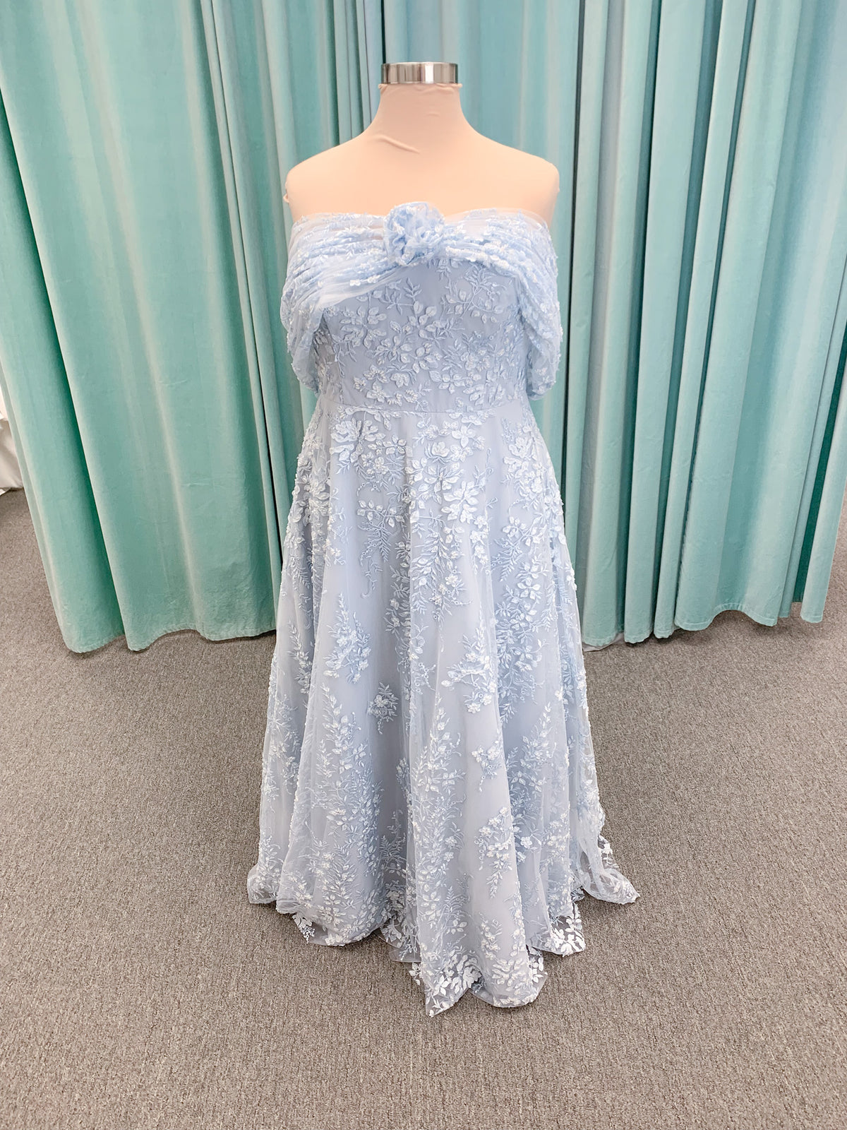 Morilee MLNY 73101 A-line mother of the bride dress on mannequin with strapless sweetheart neckline, detachable off-the-shoulder drape, 3D floral bodice, layered floral lace appliques, and full tulle skirt with pockets