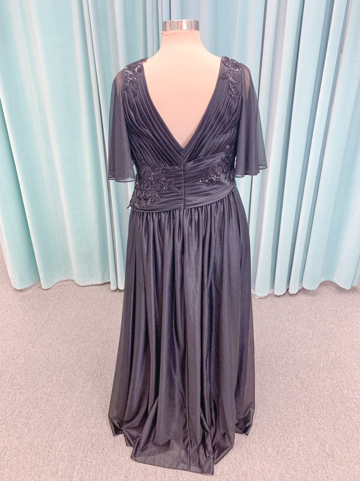 Morilee MLNY 73102 plus size A-line mother of the bride dress on mannequin with asymmetrically draped V-neck bodice, flutter sleeves, embroidered beaded appliques, and shimmer mesh A-line skirt