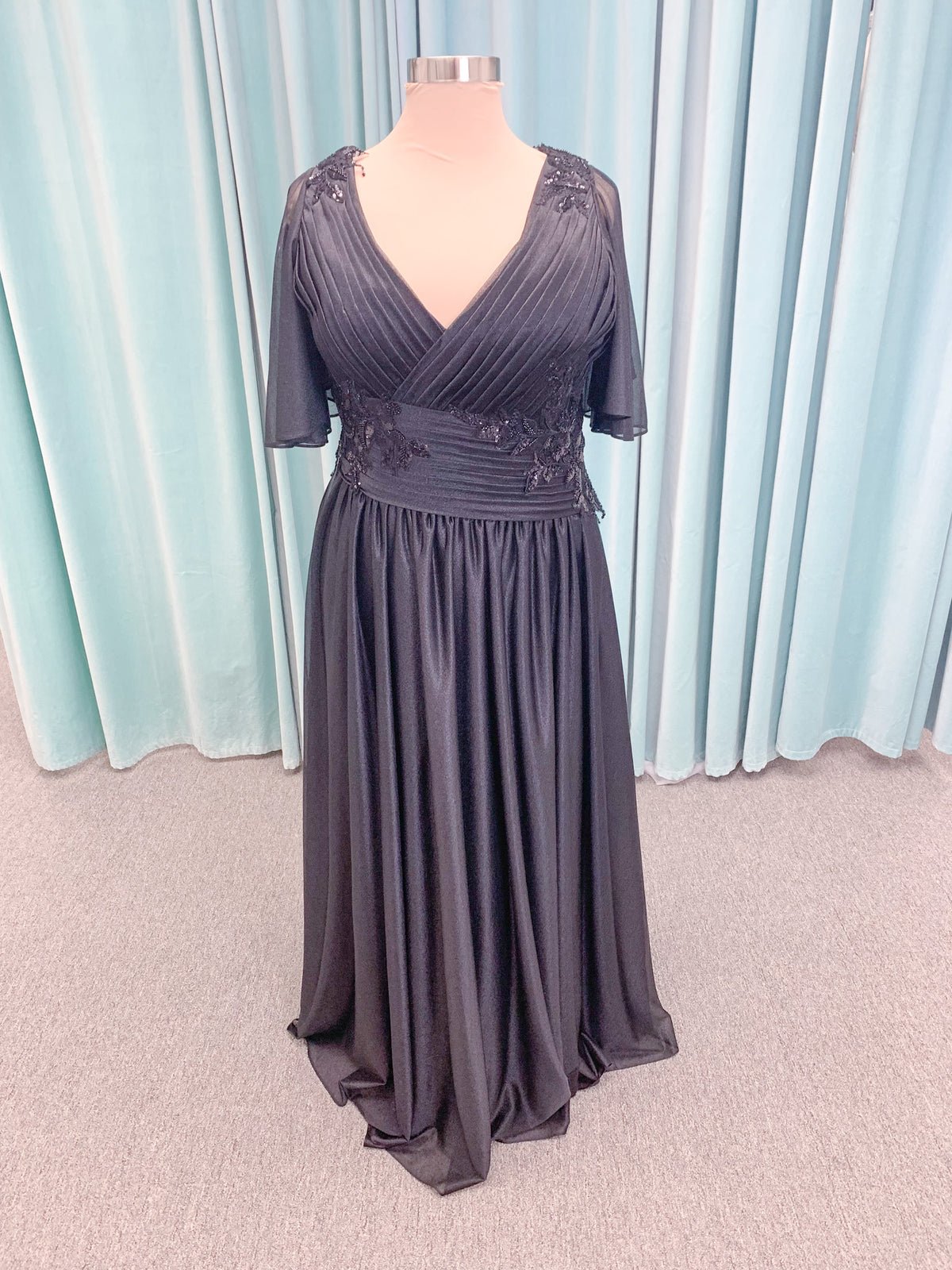Morilee MLNY 73102 plus size A-line mother of the bride dress on mannequin with asymmetrically draped V-neck bodice, flutter sleeves, embroidered beaded appliques, and shimmer mesh A-line skirt