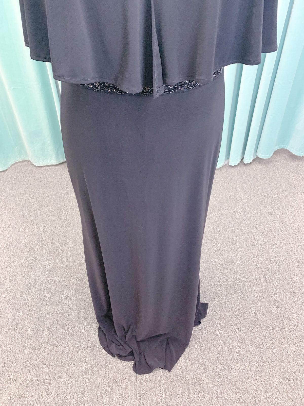Morilee MLNY 73124 sheath mother of the bride dress on mannequin with V-neckline, flowing capelet overlay, crystal beaded waistband, and slim jersey sheath skirt