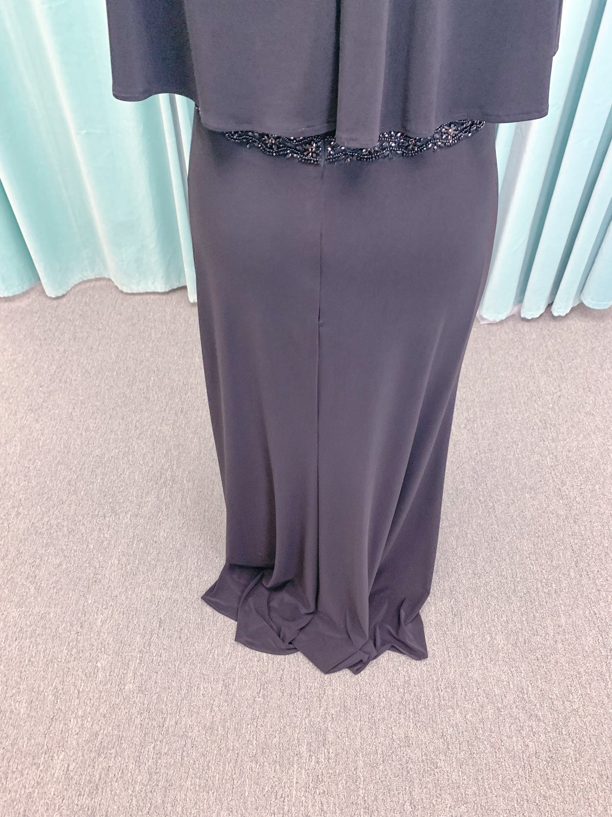Morilee MLNY 73124 sheath mother of the bride dress on mannequin with V-neckline, flowing capelet overlay, crystal beaded waistband, and slim jersey sheath skirt