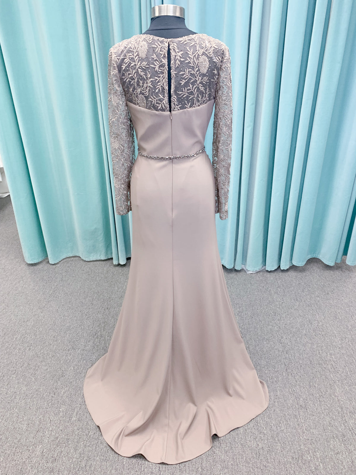 Morilee MLNY 73160 sheath mother of the bride dress on mannequin with modified sweetheart neckline, draped crepe bodice, sheer illusion long sleeves with lace applique, detachable beaded belt, and keyhole back