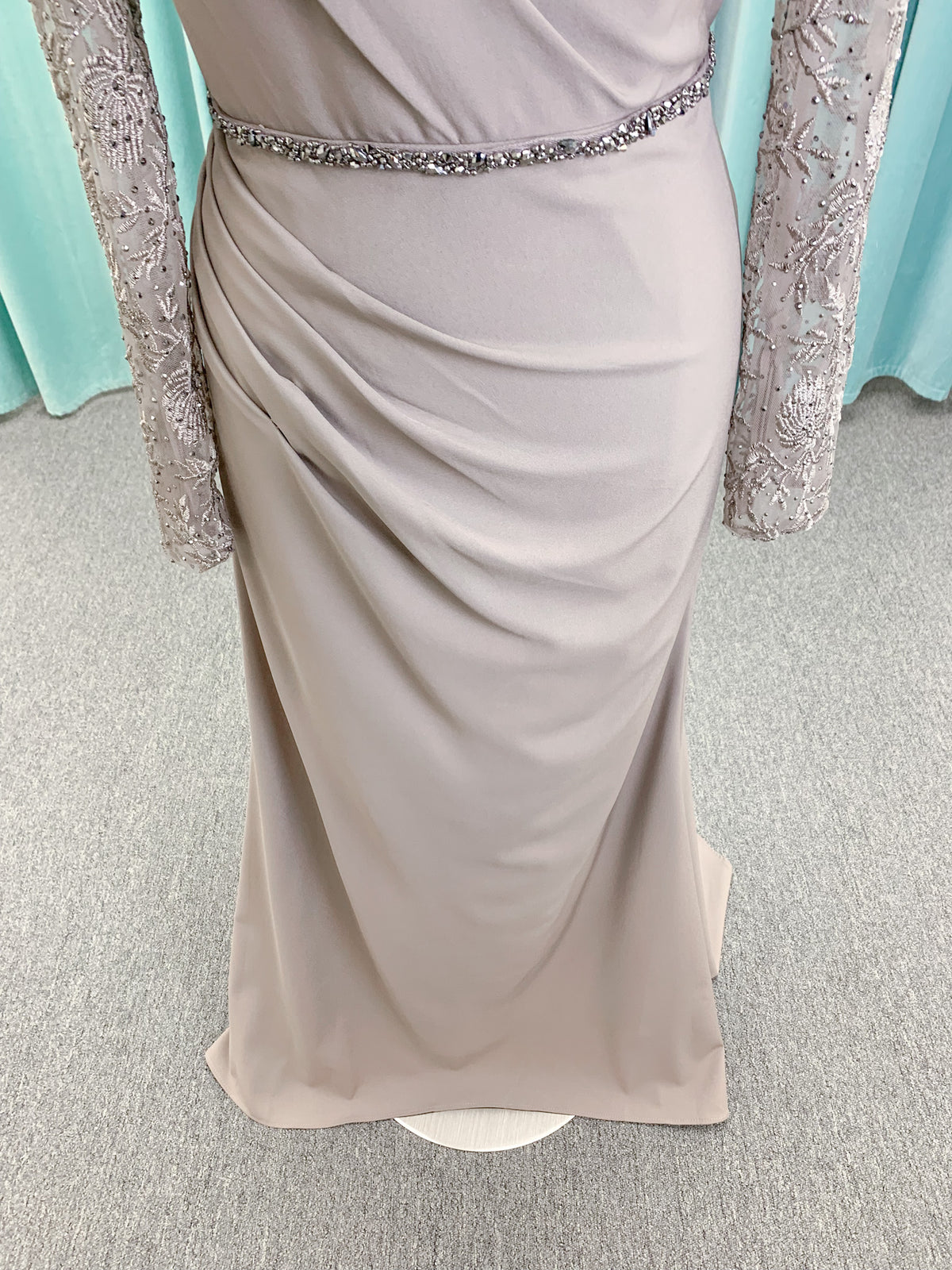 Morilee MLNY 73160 sheath mother of the bride dress on mannequin with modified sweetheart neckline, draped crepe bodice, sheer illusion long sleeves with lace applique, detachable beaded belt, and keyhole back