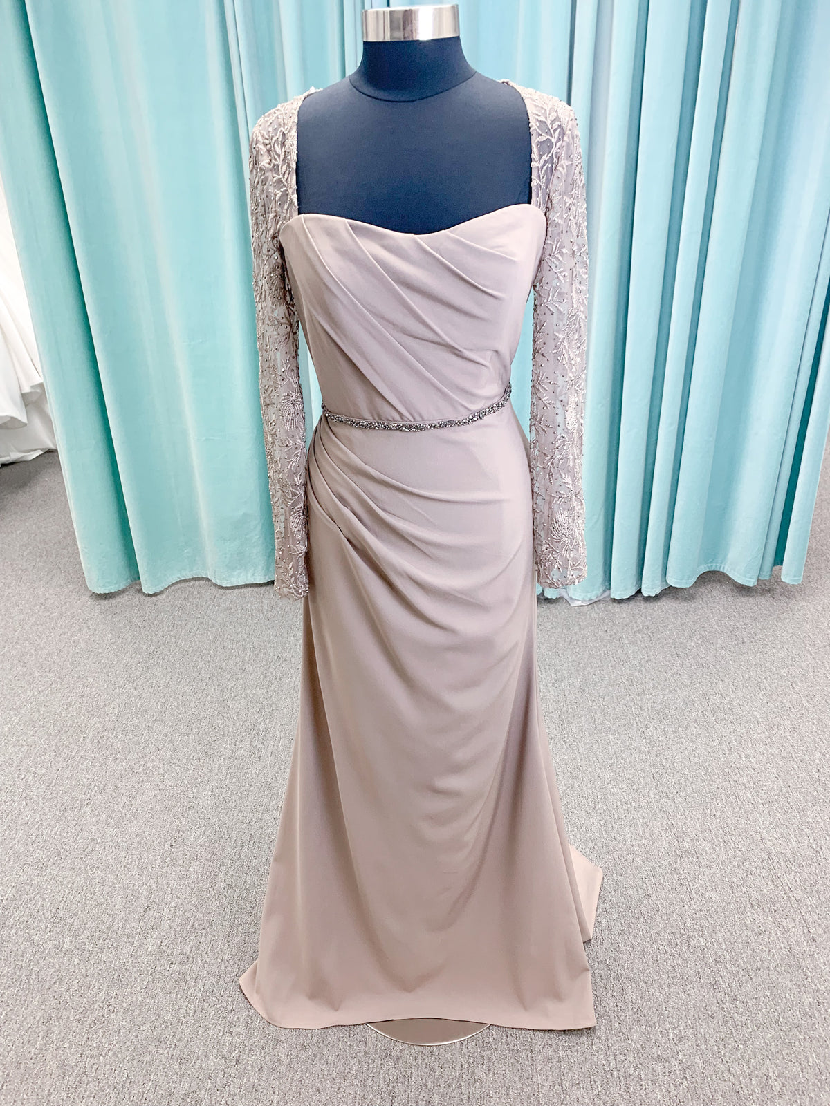 Morilee MLNY 73160 sheath mother of the bride dress on mannequin with modified sweetheart neckline, draped crepe bodice, sheer illusion long sleeves with lace applique, detachable beaded belt, and keyhole back