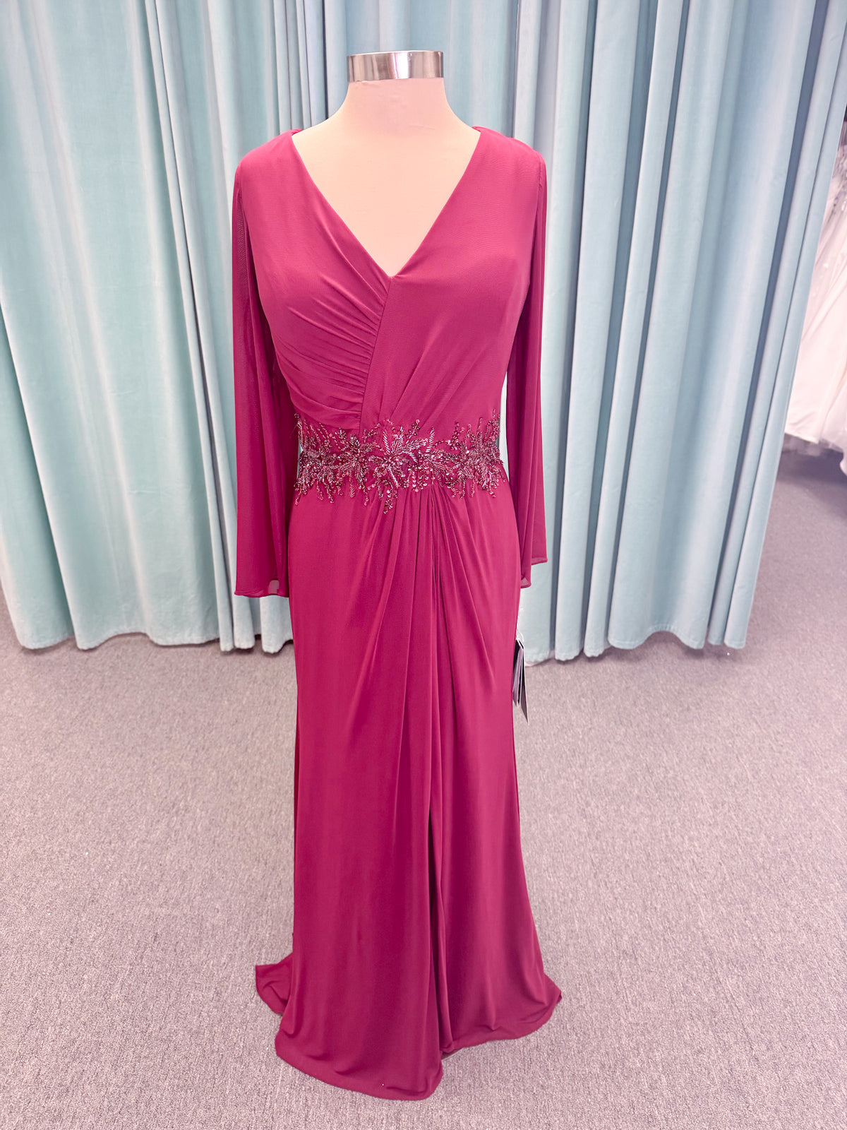 Morilee MLNY 73175 fit and flare mother of the bride dress on mannequin with draped V-neckline, long sleeves, beaded appliques, beaded waist, and slit skirt