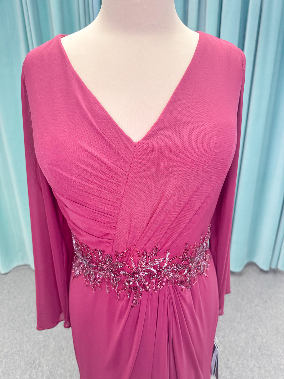 Morilee MLNY 73175 fit and flare mother of the bride dress on mannequin with draped V-neckline, long sleeves, beaded appliques, beaded waist, and slit skirt