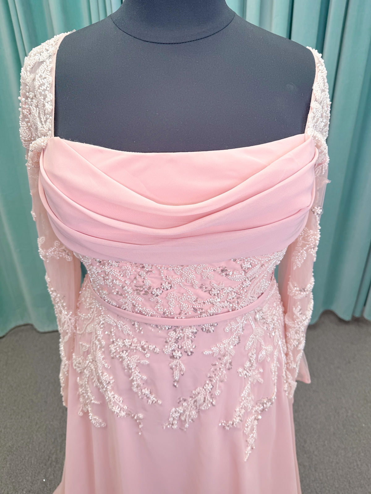  Morilee MLNY 73185 plus size A-line mother of the bride dress on mannequin with square neckline, draped chiffon bodice, sheer illusion long sleeves, beaded appliques, detachable self-belt, and flowing A-line skirt