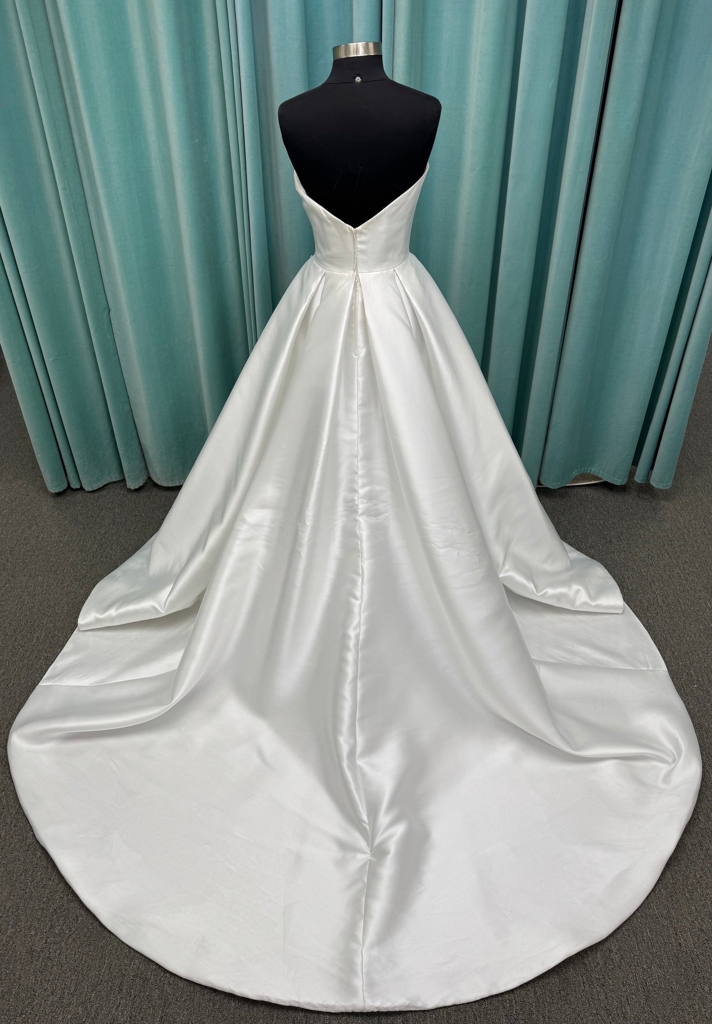 Achelios ivory strapless sweetheart satin ballgown wedding dress on mannequin with full skirt and clean structured bodice.
