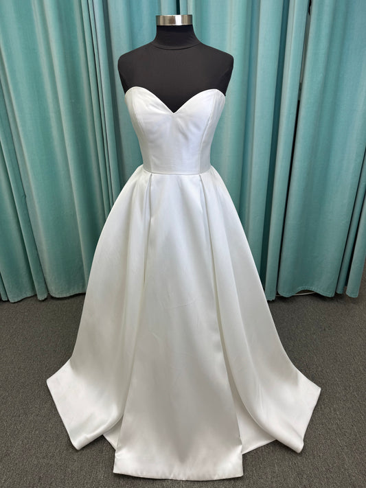 Achelios ivory strapless sweetheart satin ballgown wedding dress on mannequin with full skirt and clean structured bodice.
