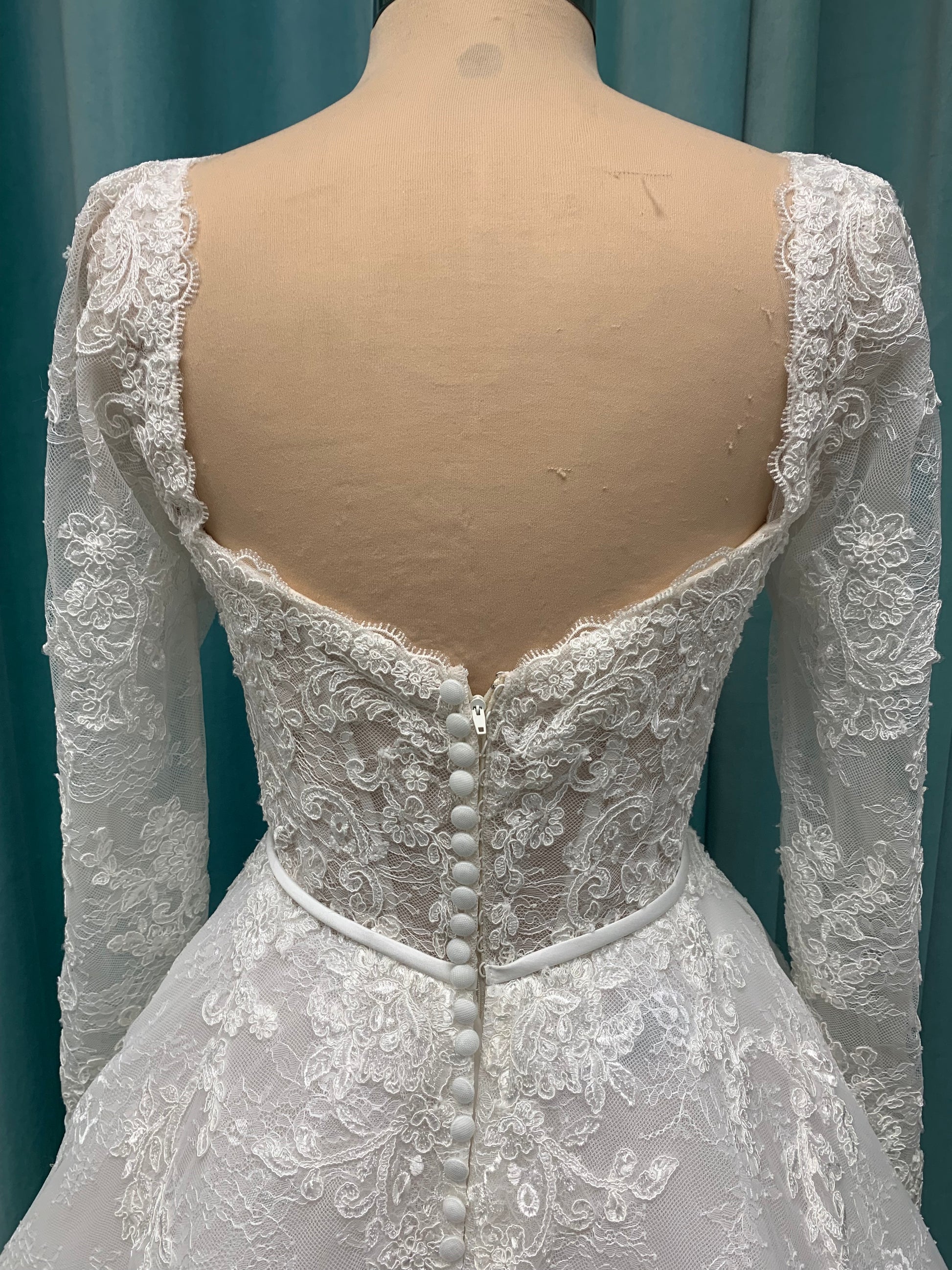 Morilee Sannah 2750 ball gown with strapless sweetheart neckline, lace corset bodice, satin bow waistband, and full tulle skirt with scalloped hem and long sleeves