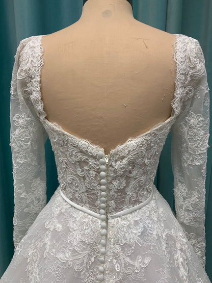 Morilee Sannah 2750 ball gown with strapless sweetheart neckline, lace corset bodice, satin bow waistband, and full tulle skirt with scalloped hem and long sleeves