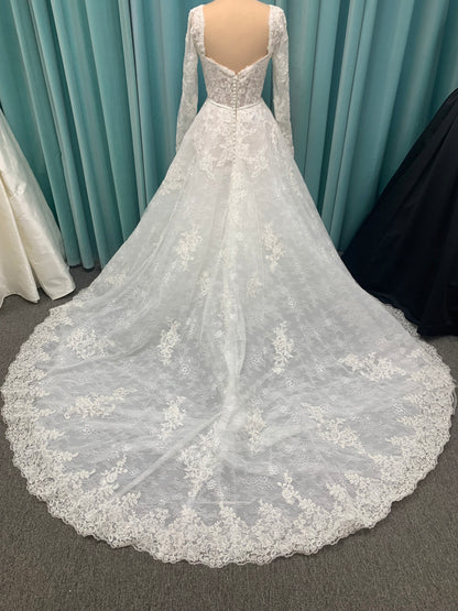 Morilee Sannah 2750 ball gown with strapless sweetheart neckline, lace corset bodice, satin bow waistband, and full tulle skirt with scalloped hem and long sleeves