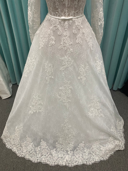 Morilee Sannah 2750 ball gown with strapless sweetheart neckline, lace corset bodice, satin bow waistband, and full tulle skirt with scalloped hem and long sleeves