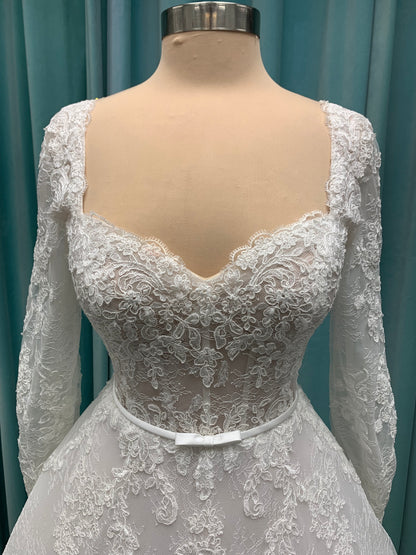 Morilee Sannah 2750 ball gown with strapless sweetheart neckline, lace corset bodice, satin bow waistband, and full tulle skirt with scalloped hem and long sleeves