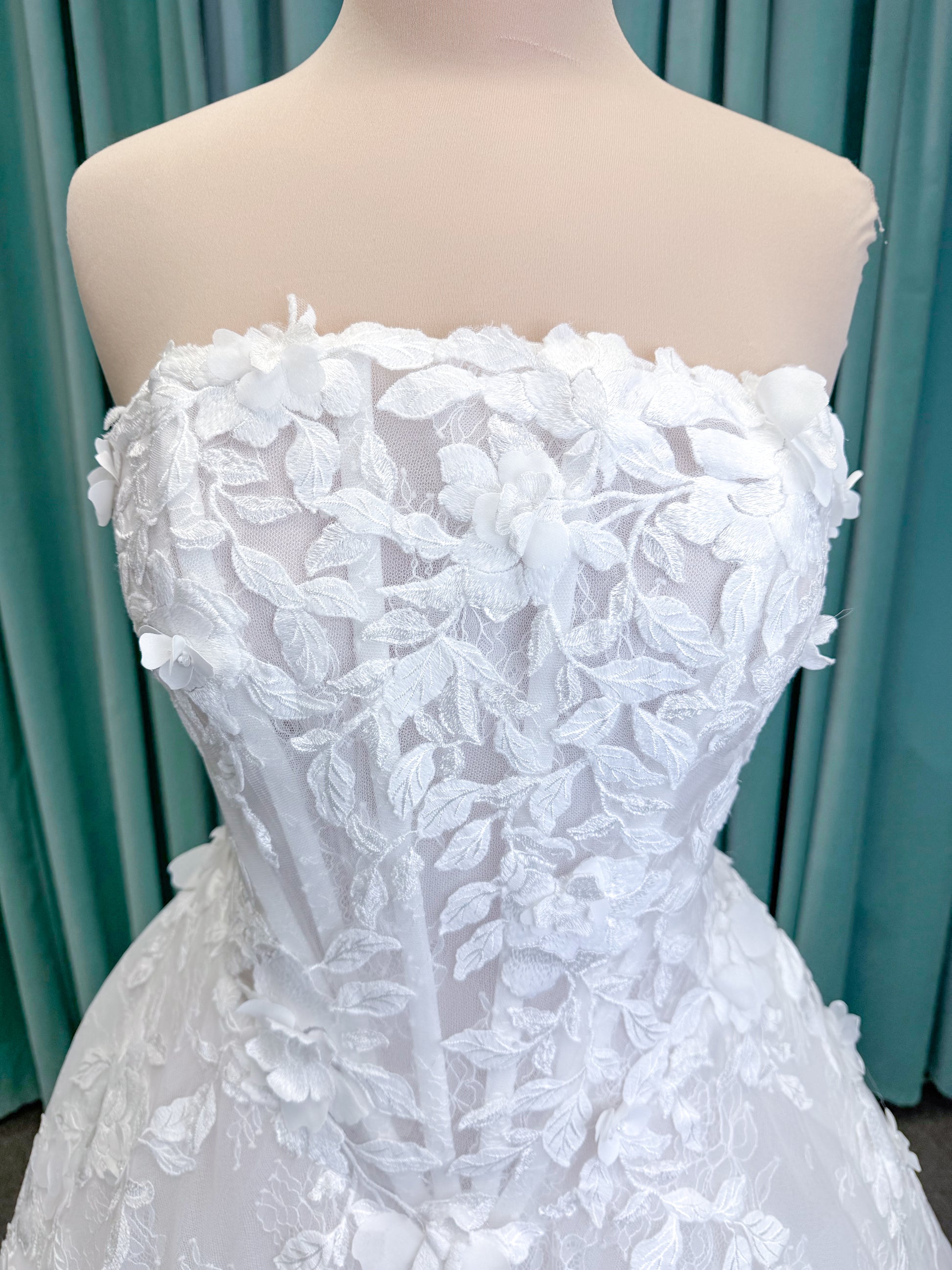 Morilee 1010024 Alina A-line wedding dress on mannequin with strapless basque waist, corset boning, Chantilly lace, and hand-cut taffeta flowers