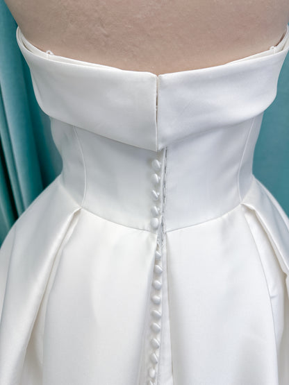 Morilee 1050011 Allegro A-line wedding dress on mannequin with strapless straight neckline, Mikado fabric, box-pleated skirt, and detachable fold-over bow