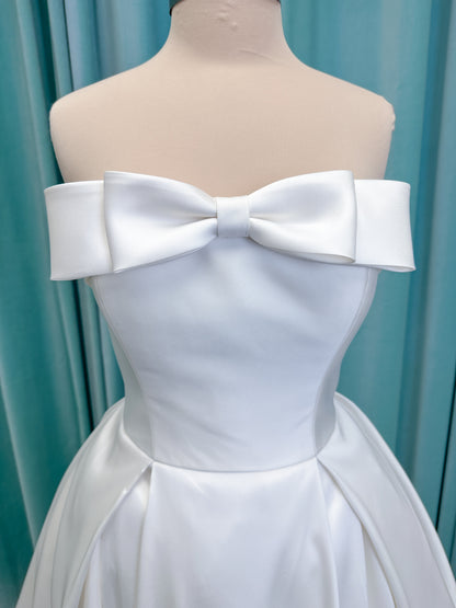 Morilee 1050011 Allegro A-line wedding dress on mannequin with strapless straight neckline, Mikado fabric, box-pleated skirt, and detachable fold-over bow
