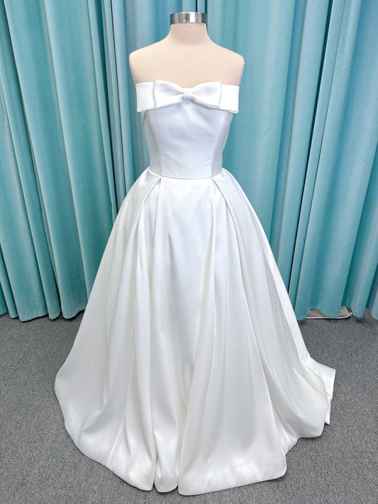 Morilee 1050011 Allegro A-line wedding dress on mannequin with strapless straight neckline, Mikado fabric, box-pleated skirt, and detachable fold-over bow