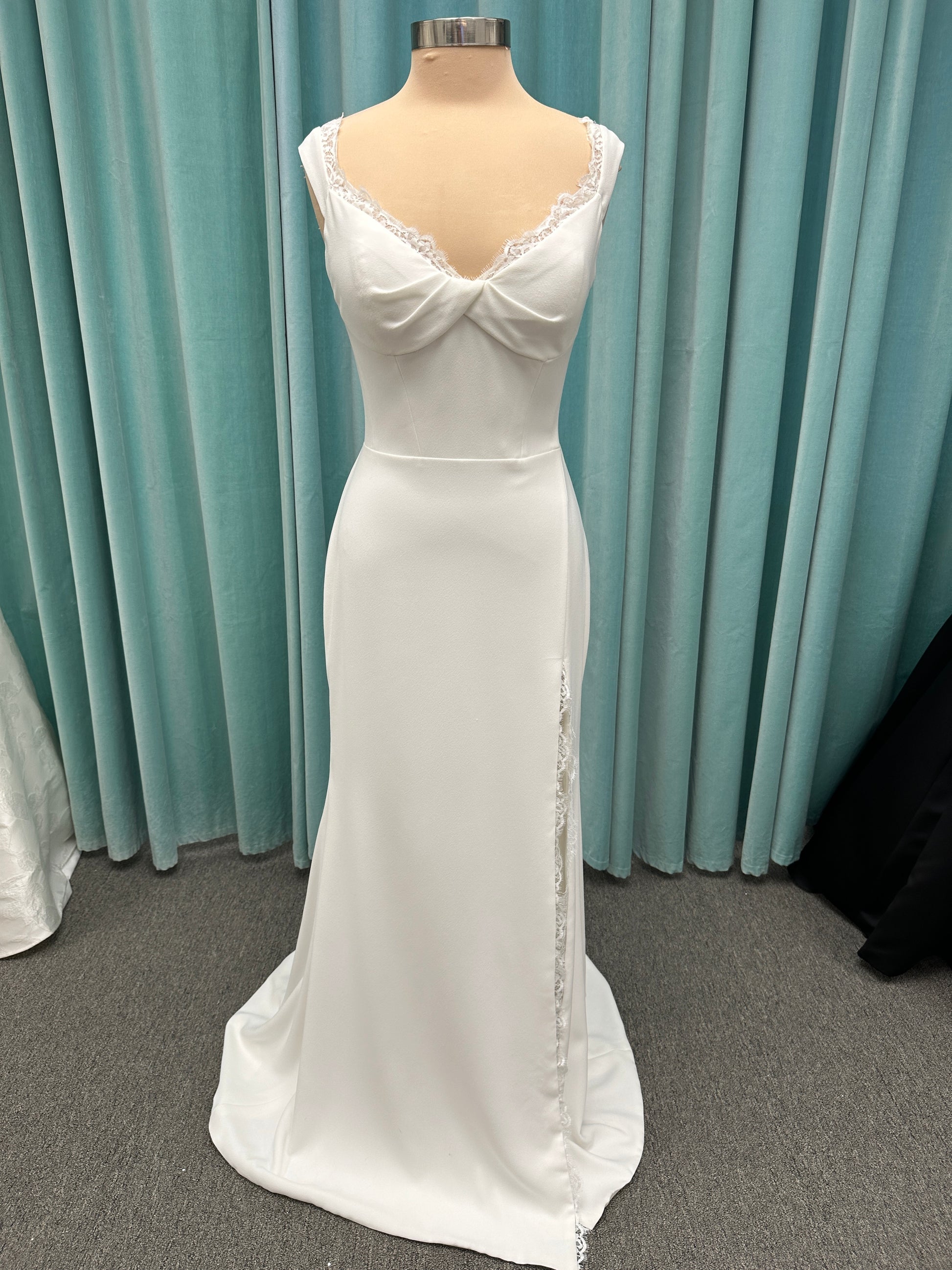 Morilee Scottie wedding dress Style 2711 with off-the-shoulder neckline, twist draped bodice, and lace-trimmed sheath skirt with slit