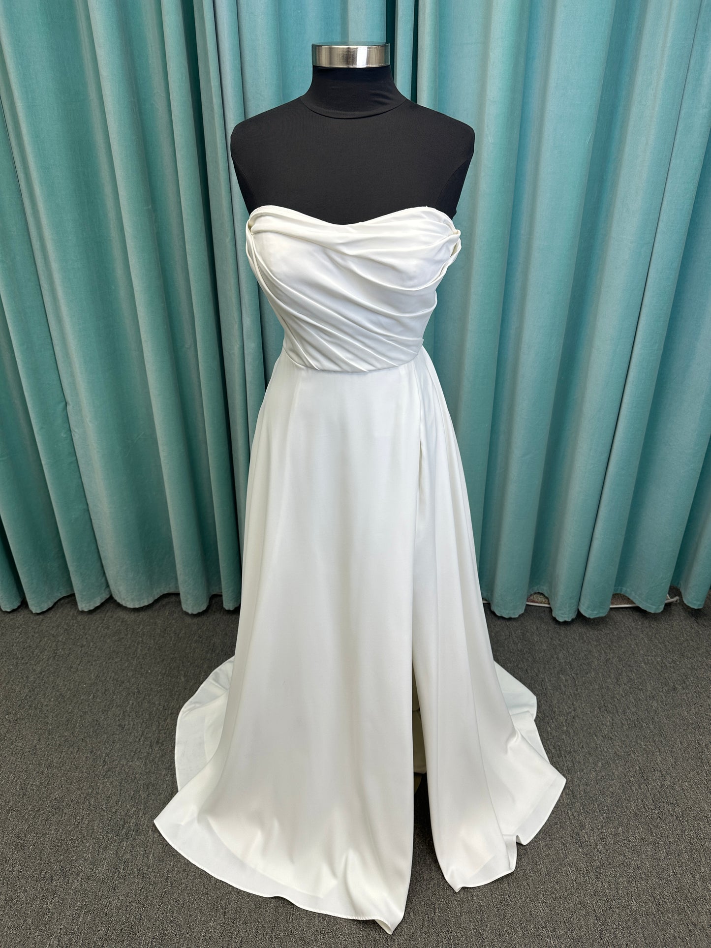 Essense of Australia D4225 ivory satin A-line wedding dress on mannequin with strapless scoop neckline, ruched bodice, and a front slit in the skirt.
