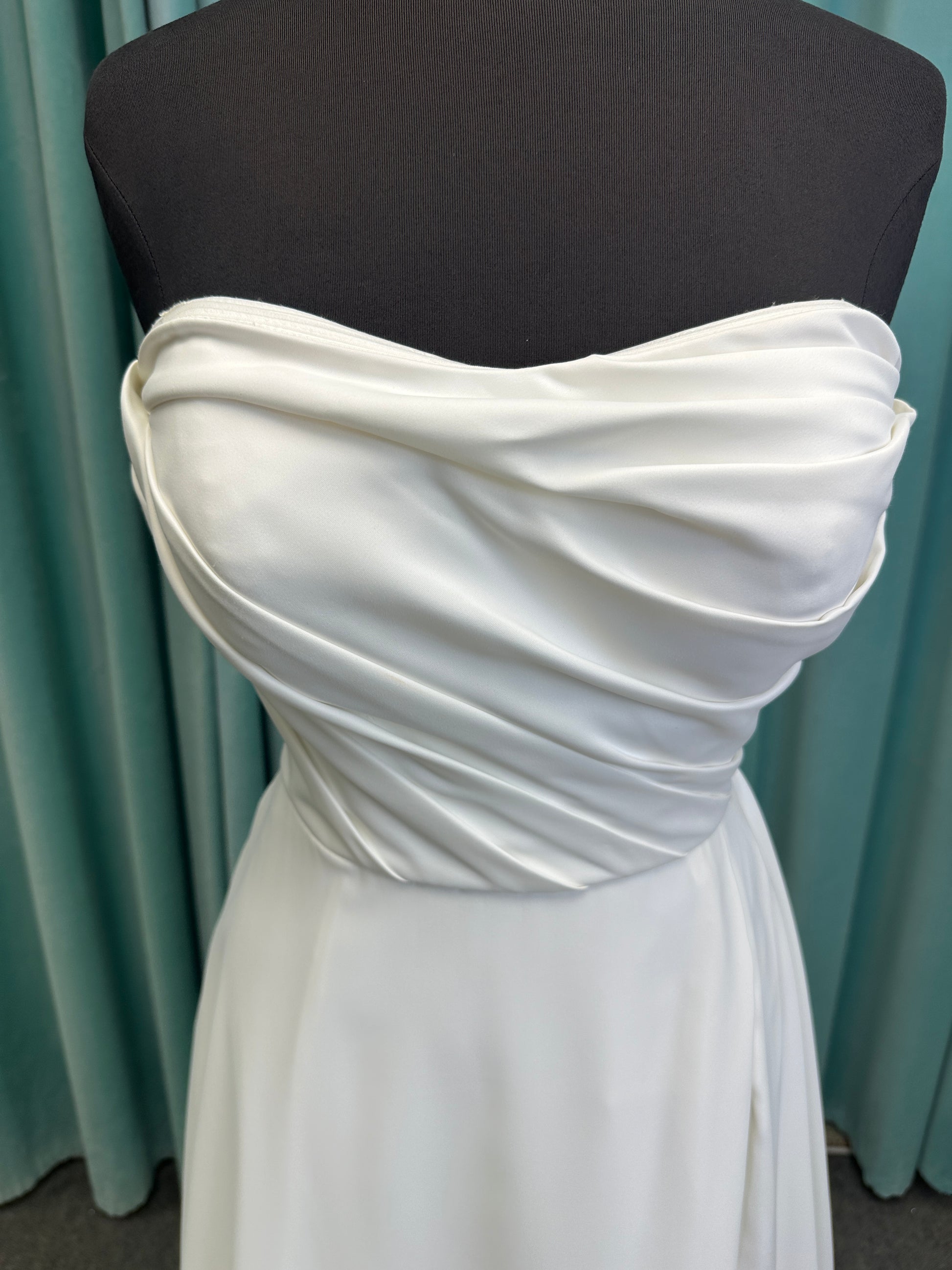 Essense of Australia D4225 ivory satin A-line wedding dress on mannequin with strapless scoop neckline, ruched bodice, and a front slit in the skirt.
