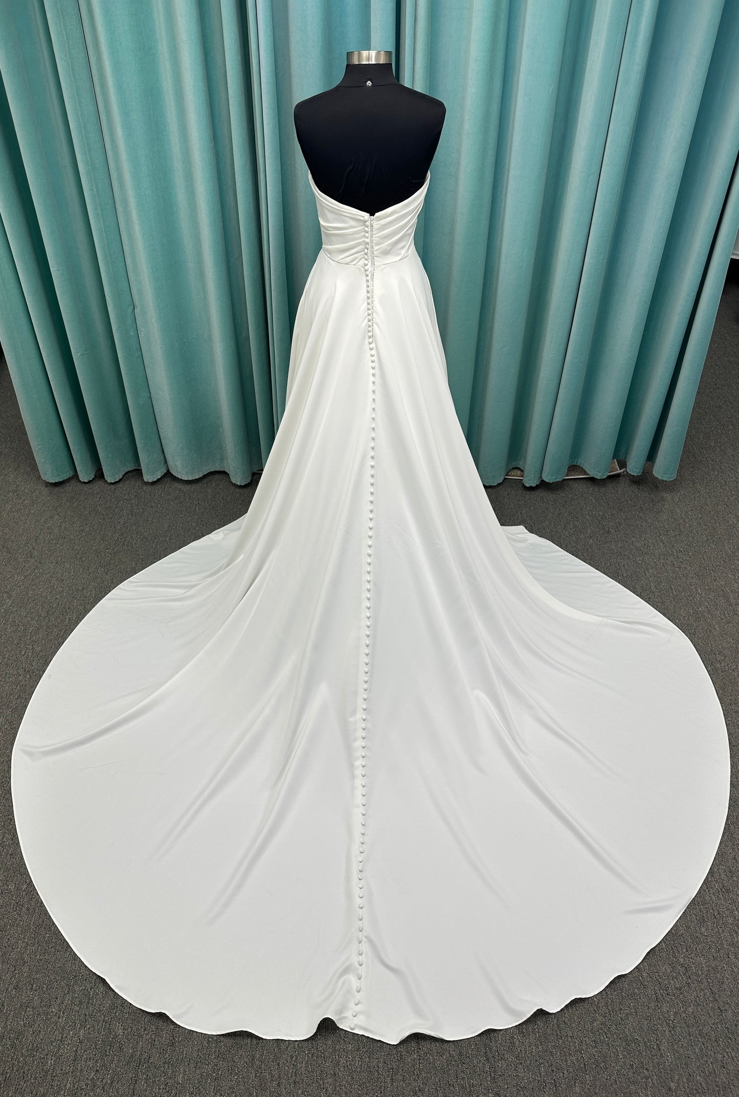 Essense of Australia D4225 ivory satin A-line wedding dress on mannequin with strapless scoop neckline, ruched bodice, and a front slit in the skirt.

