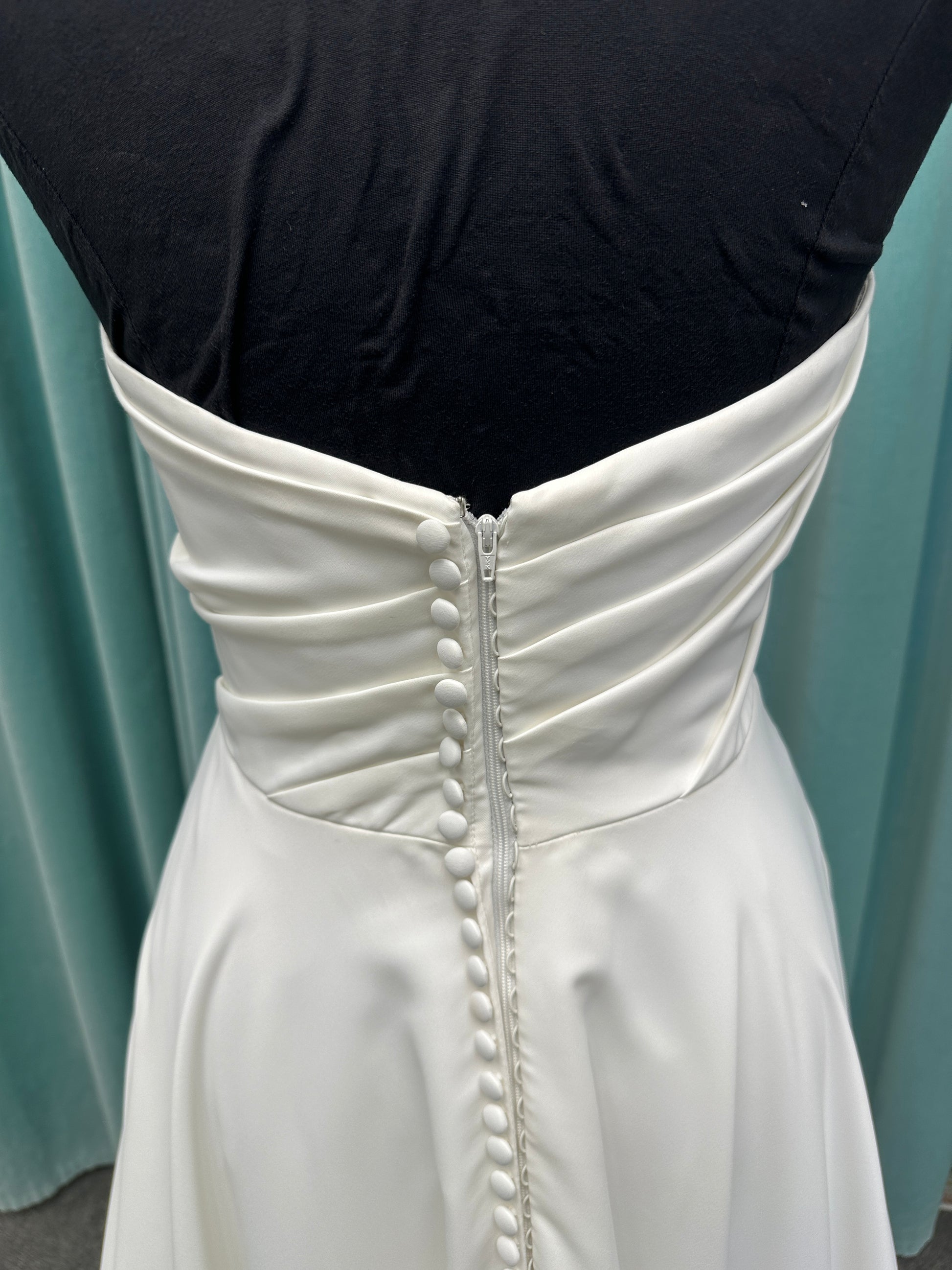 Essense of Australia D4225 ivory satin A-line wedding dress on mannequin with strapless scoop neckline, ruched bodice, and a front slit in the skirt.
