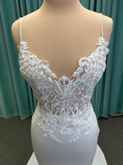 Calliope ivory spaghetti strap V-neck fit-and-flare wedding dress on mannequin with 3D floral lace appliqué bodice and sleek crepe skirt.
