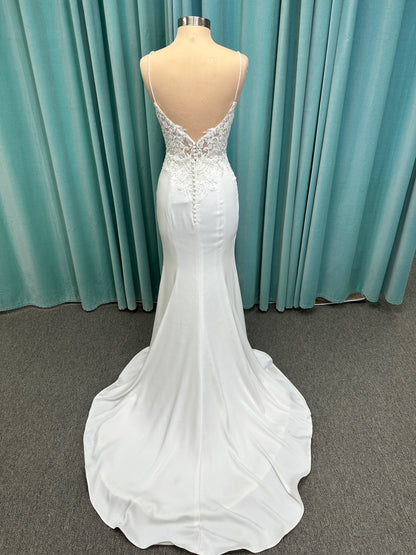 Calliope ivory spaghetti strap V-neck fit-and-flare wedding dress on mannequin with 3D floral lace appliqué bodice and sleek crepe skirt.
