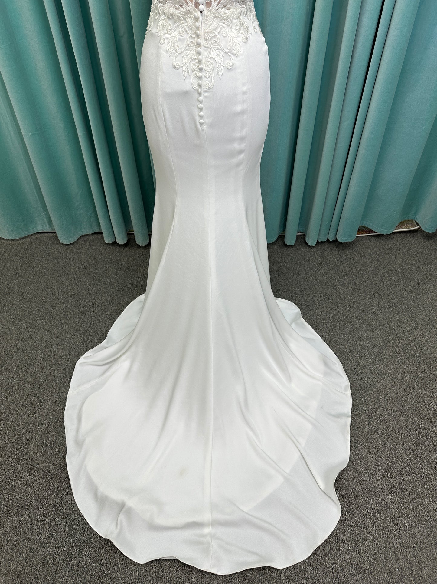 Calliope ivory spaghetti strap V-neck fit-and-flare wedding dress on mannequin with 3D floral lace appliqué bodice and sleek crepe skirt.
