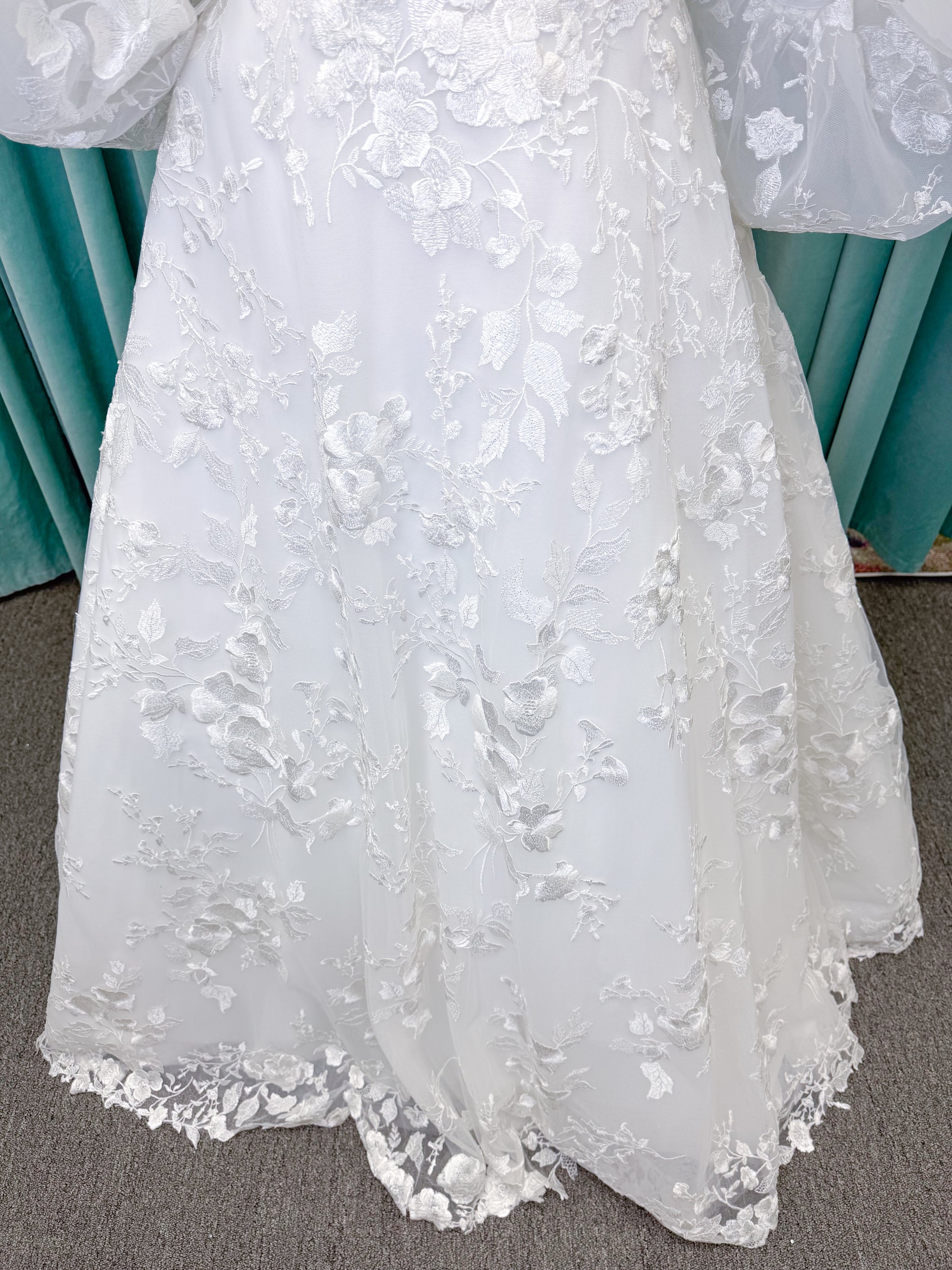 Morilee 2987 Callyso A-line wedding dress on mannequin with strapless tulle, floral threadwork, detachable puff sleeves, and flowing train