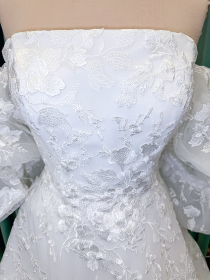 Morilee 2987 Callyso A-line wedding dress on mannequin with strapless tulle, floral threadwork, detachable puff sleeves, and flowing train