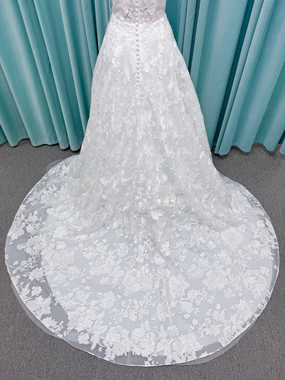 Moonlight Bridal J6818 Channary A-line wedding dress on mannequin with sweetheart illusion neckline, large floral embroidered lace with sequins, off-the-shoulder lace swag sleeves, full net skirt, and chapel train