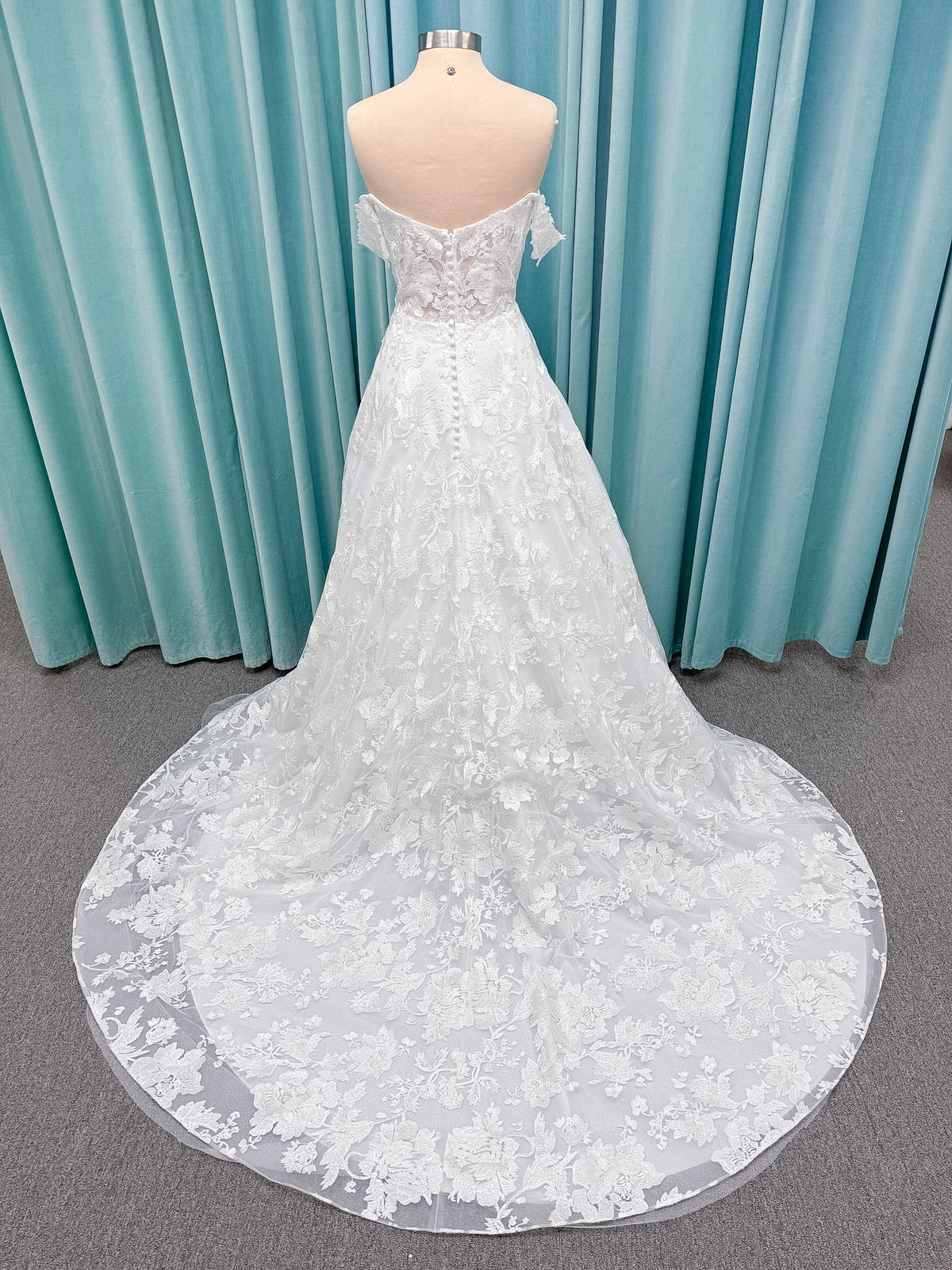 Moonlight Bridal J6818 Channary A-line wedding dress on mannequin with sweetheart illusion neckline, large floral embroidered lace with sequins, off-the-shoulder lace swag sleeves, full net skirt, and chapel train