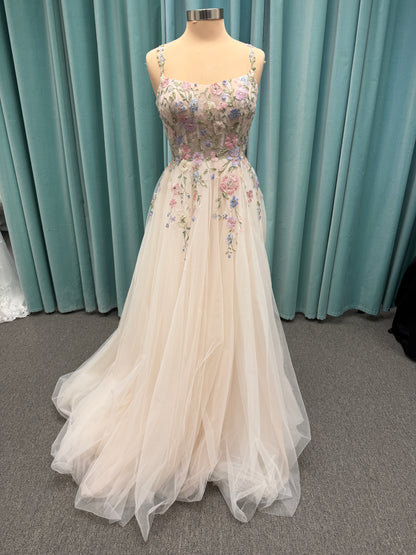 Stella York 8063 ivory and pastel colorful embroidered lace A-line wedding dress on mannequin with floral spaghetti straps, scoop neckline, and soft tulle skirt.
