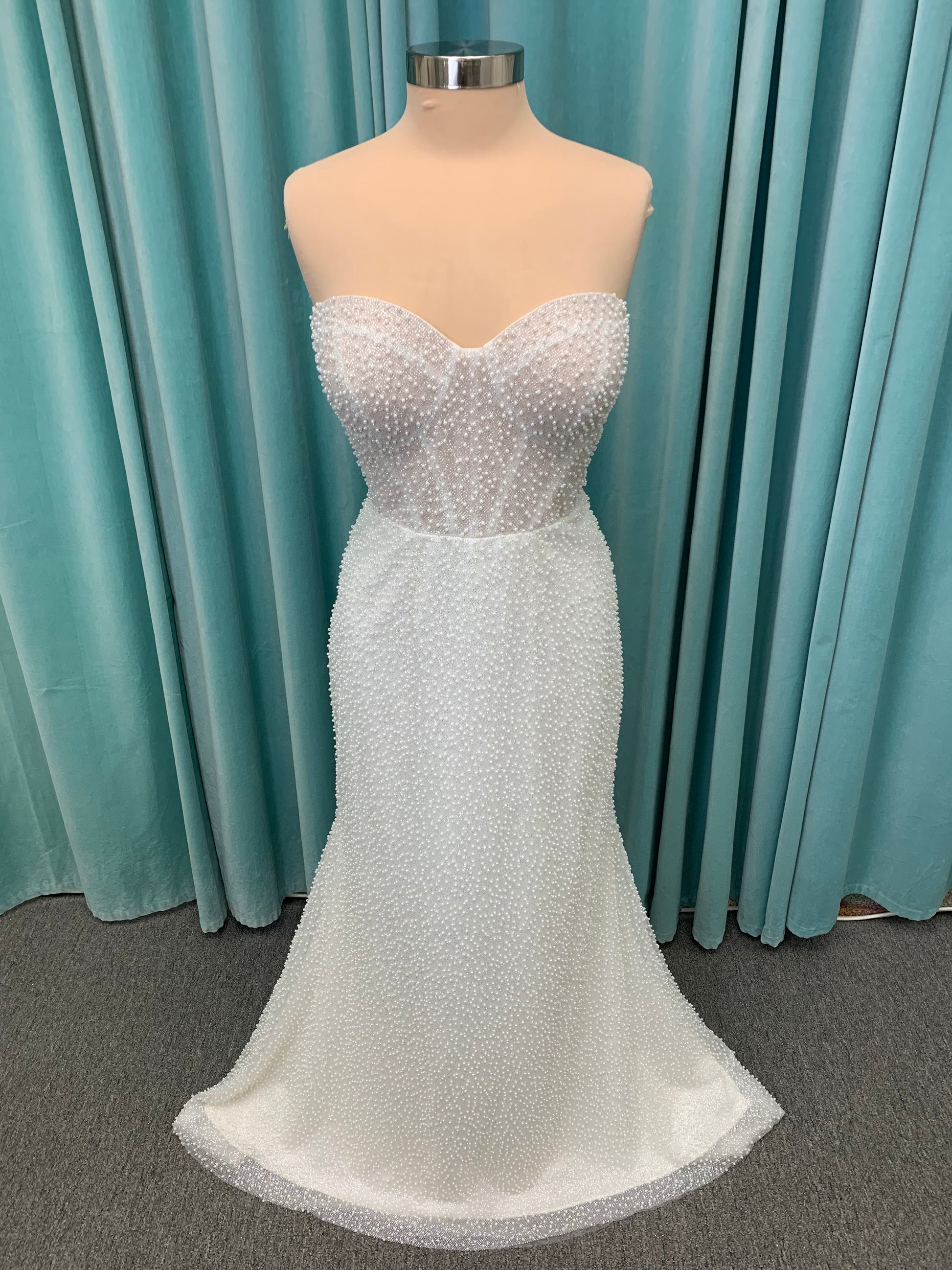 Cynthia ivory strapless fit-and-flare wedding dress on mannequin with pearl-beaded corset bodice and sweetheart neckline.
