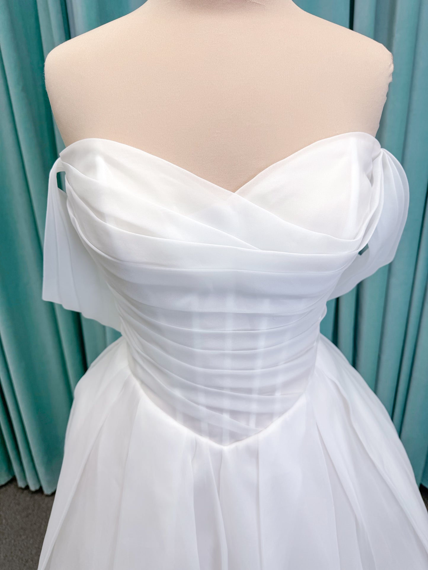 Morilee 2947L Damara A-line wedding dress on mannequin with modified sweetheart neckline, off-the-shoulder detailing, organza box pleats, and corset back