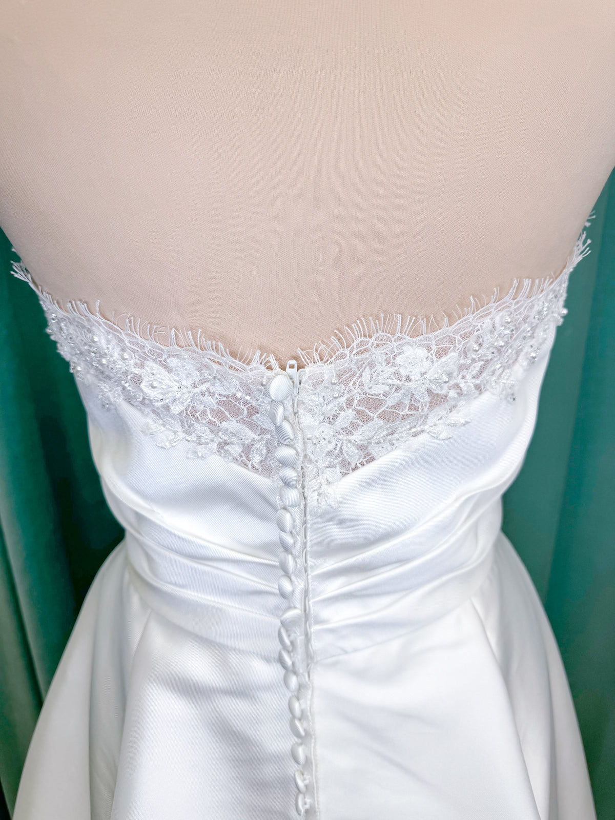 Morilee 1010001 Dove ballgown wedding dress on mannequin with strapless scoop neckline, lace peek-a-boo detail, and softly pleated skirt