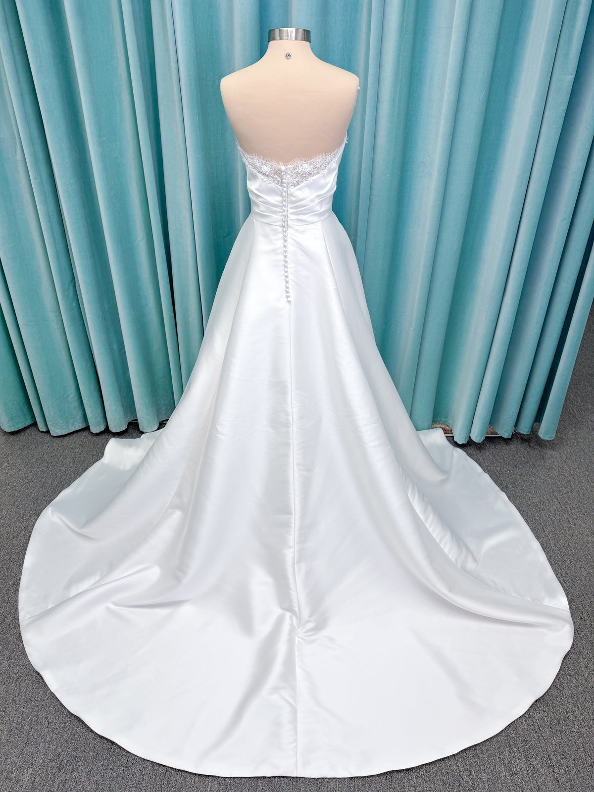 Morilee 1010001 Dove ballgown wedding dress on mannequin with strapless scoop neckline, lace peek-a-boo detail, and softly pleated skirt