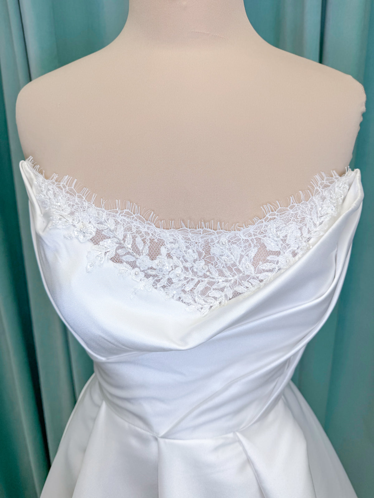 Morilee 1010001 Dove ballgown wedding dress on mannequin with strapless scoop neckline, lace peek-a-boo detail, and softly pleated skirt