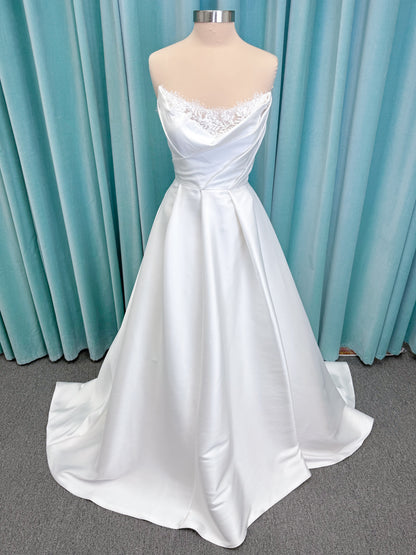 Morilee 1010001 Dove ballgown wedding dress on mannequin with strapless scoop neckline, lace peek-a-boo detail, and softly pleated skirt