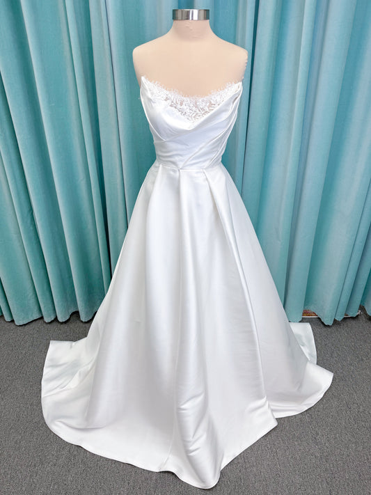 Morilee 1010001 Dove ballgown wedding dress on mannequin with strapless scoop neckline, lace peek-a-boo detail, and softly pleated skirt