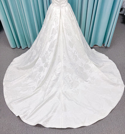 Strapless floral jacquard ballgown wedding dress with a sweetheart neckline, ruched bodice, defined waist, and full structured skirt.