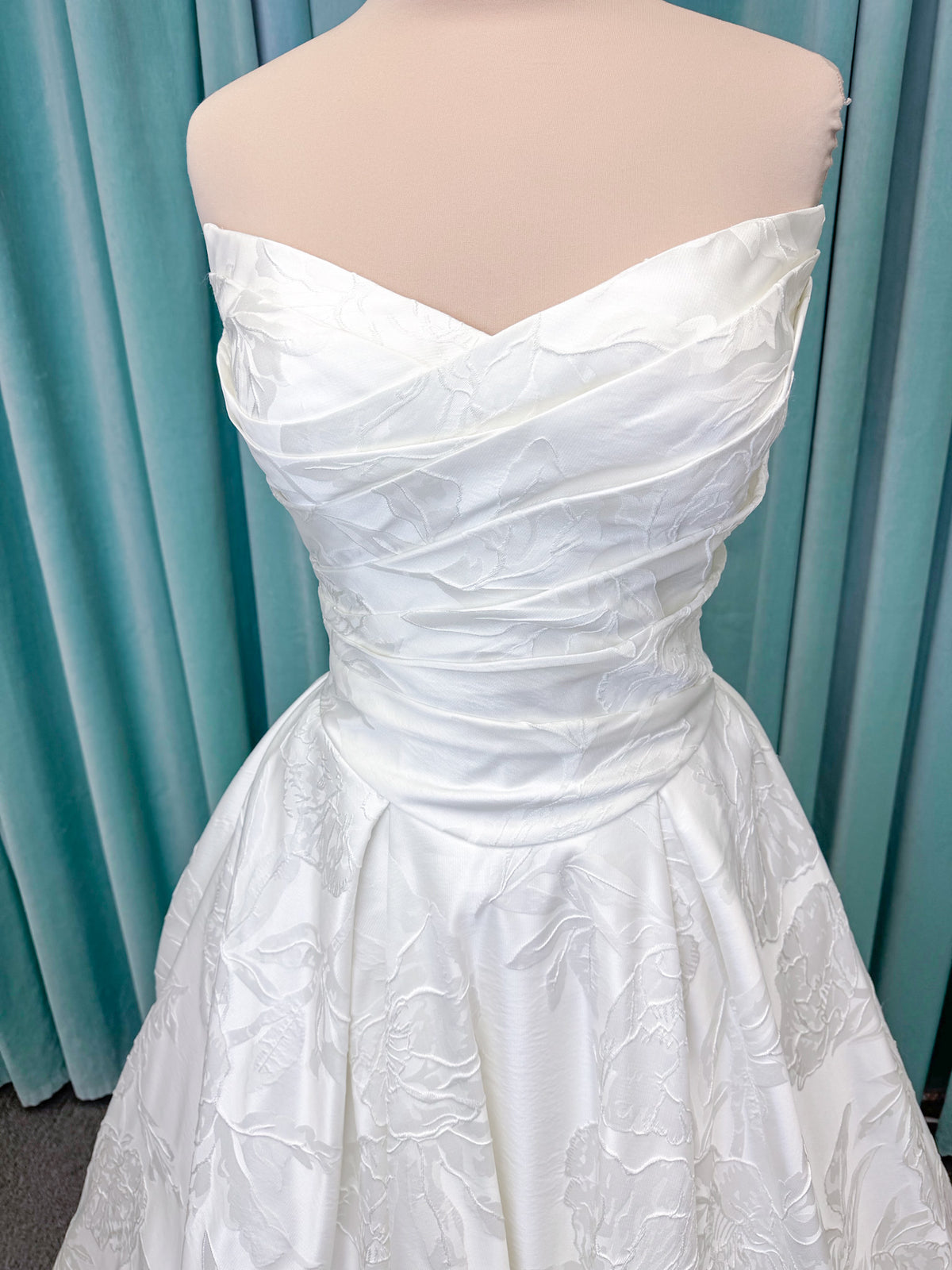 Strapless floral jacquard ballgown wedding dress with a sweetheart neckline, ruched bodice, defined waist, and full structured skirt.