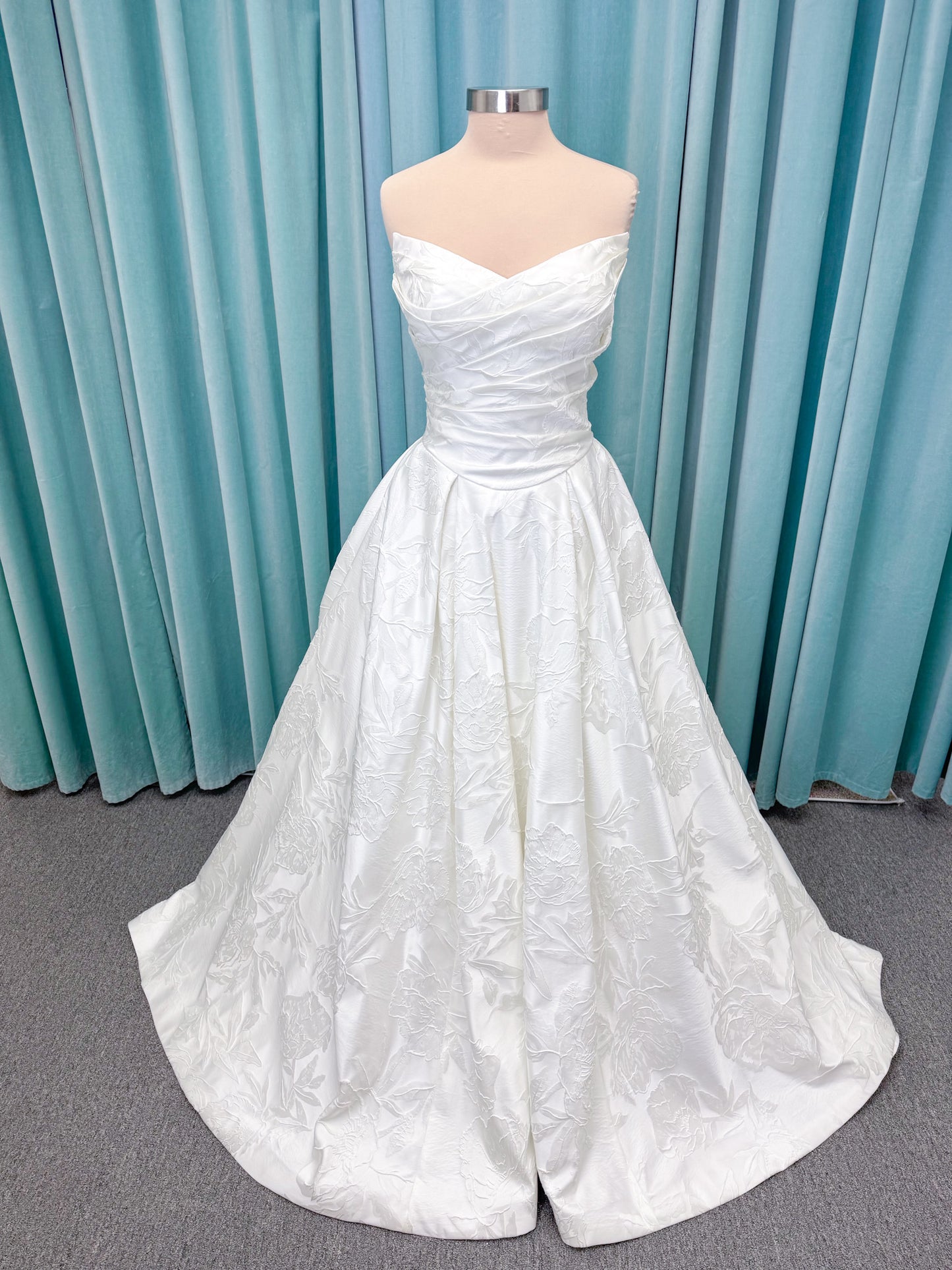 Strapless floral jacquard ballgown wedding dress with a sweetheart neckline, ruched bodice, defined waist, and full structured skirt.